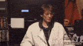 a man in a white coat is sitting in front of a lg tv