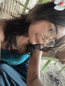 a woman wearing glasses and a flower in her hair takes a selfie