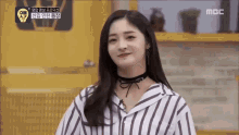 a woman wearing a striped shirt and a choker is smiling