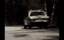 a car with a red light on top of it is driving down a road .