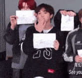 a group of young men are holding up pieces of paper one of which has the letter v on it