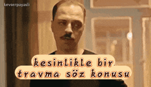a man with a mustache is smoking a cigarette and says " kesinlikle bir travma söz konuşu "