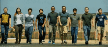 a group of people walking in a line with one wearing a shirt that says genius