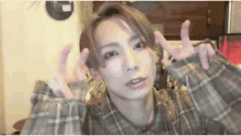 a young man wearing a plaid shirt is making a funny face