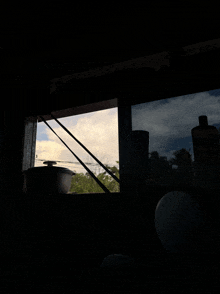 a window with a view of a cloudy sky and trees