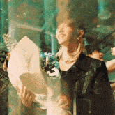 a woman in a black leather jacket holds a bouquet of flowers