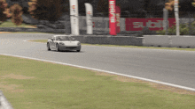 a silver car is driving down a race track with a red sign that says ' stib ' on it