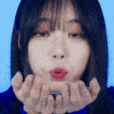 a woman blowing a kiss with her hands on her face