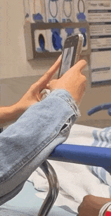 a person is holding a cell phone in their hand while sitting in a hospital bed .