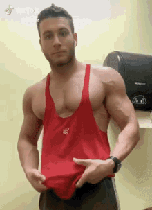a man in a red tank top is standing in front of a paper dispenser .