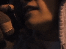 a close up of a person 's face with a glass of wine in their hand .