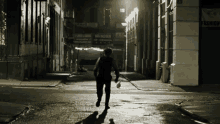 a man walking down a dark street with a sign that says ' cafe & bakery ' on it