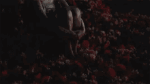 a woman is sitting in a field of red flowers at night .