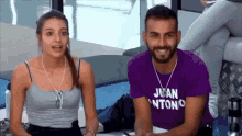 a man and a woman are sitting next to each other and the man is wearing a juan antonio shirt