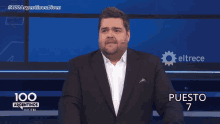 a man in a suit stands in front of a screen that says 100 argentinas dicen