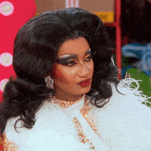 a drag queen is wearing a white feathered coat