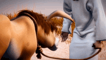 a man in a white robe is holding a rope around a horse 's neck