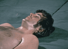 a man without a shirt is laying on a bed