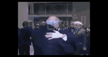 a man in a suit is hugging another man in a suit in front of a crowd of people .