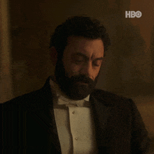 a man with a beard wearing a tuxedo and bow tie with hbo written in the corner