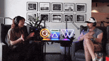 a man and a woman are sitting in front of a microphone in front of a neon sign that says o and w