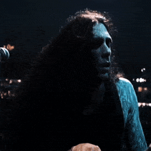 a man with long curly hair sings into a microphone