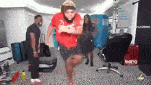 a man in a red shirt is dancing in a room with other people