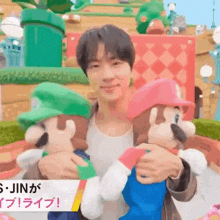 a man is holding two mario dolls in his arms in a video game park .