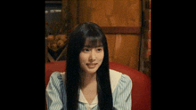 a woman with long black hair is sitting on a red couch in a restaurant .
