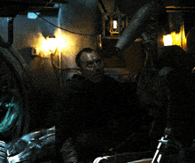 a man is standing in a dark room with a light on the wall