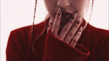 a woman wearing a red sweater with black nails