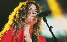 a woman is singing into a microphone with a yellow background