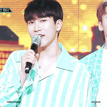 a man in a green and white striped shirt is holding a microphone in his mouth