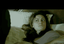 a woman is laying on a bed with a pillow on her head