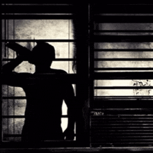 a silhouette of a man standing in front of a window .