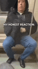 a man in a hooded jacket is sitting on a train with the words my honest reaction written above him