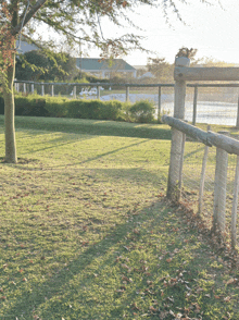 a wooden fence surrounds a grassy area with a sign that says ' lgc ' on it