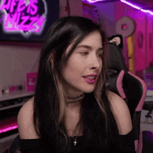 a woman with long black hair is sitting in a pink chair in front of a computer .