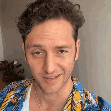 a close up of a man 's face wearing a colorful shirt and necklace .