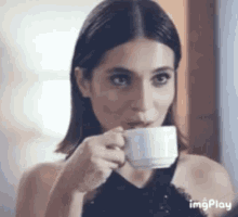 a woman is drinking a cup of coffee from a cup .