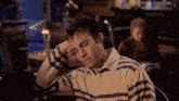 a man wearing a striped shirt is sleeping with his eyes closed