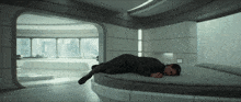 a man is laying on a bed in a room with a large window