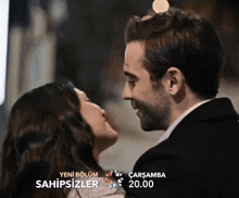 a man and a woman are kissing in front of a sign that says yeni bölüm sahipsizler