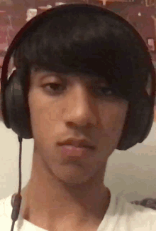 a young man wearing headphones looks at the camera with a serious look on his face