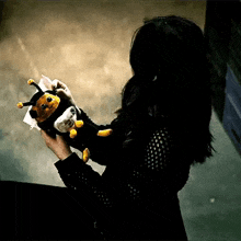 a woman is holding a stuffed bee in her hand .