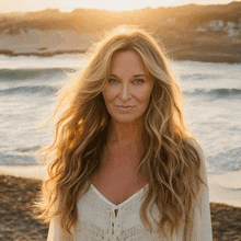 a woman with long blonde hair stands on the beach