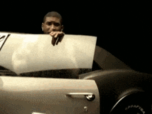 a man is sitting in a car and holding a piece of paper .