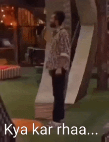 a man is standing in front of a slide in a room with a sign that says kya kar rhaa .