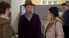 a man in a hat is standing next to a woman in a trench coat