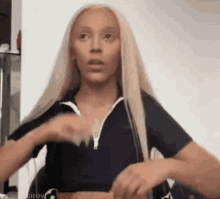 a woman with long blonde hair is wearing a black crop top and a black jacket .